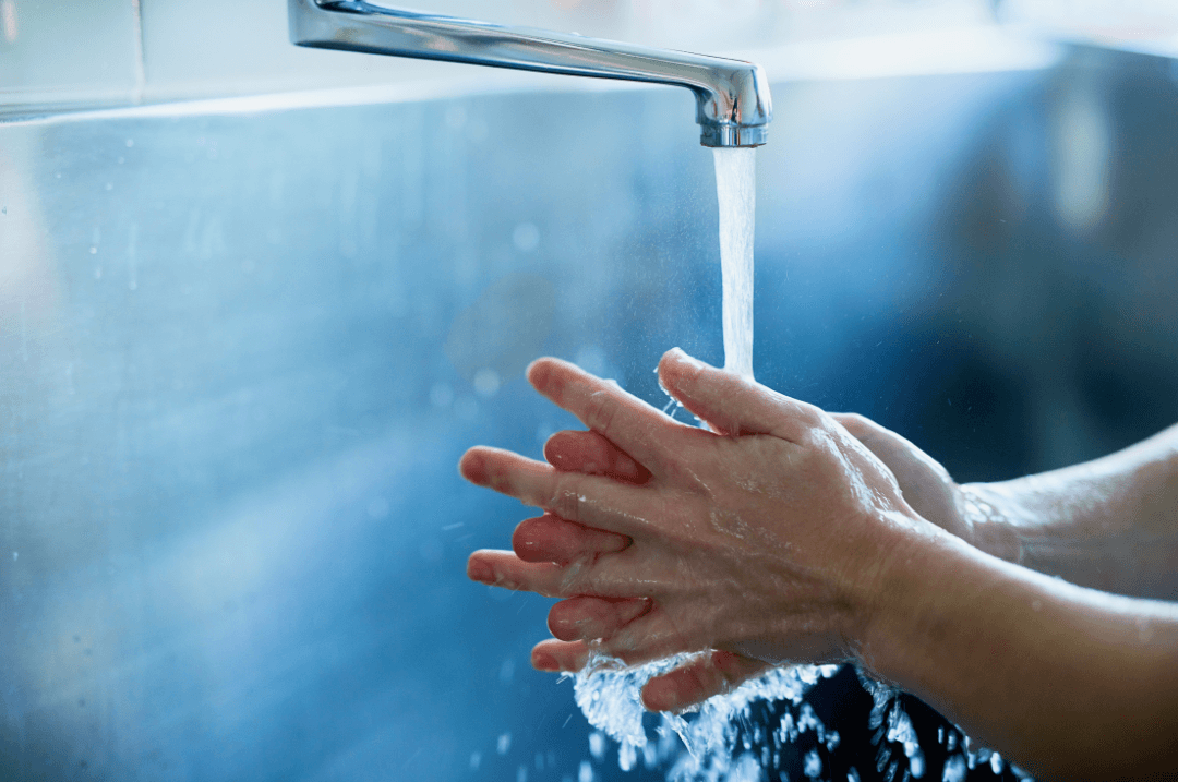 Lavage des mains à l’eau courante sur un lave-mains en inox de cuisine professionnelle