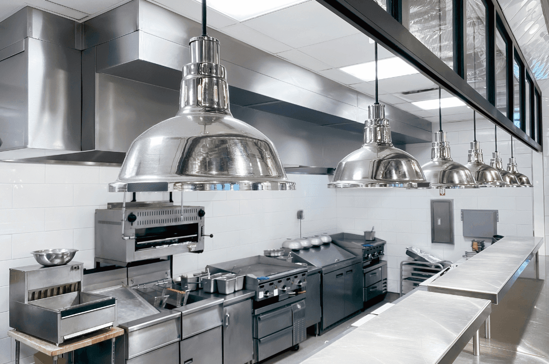 Cuisine professionnelle vide en ordre de marche, hottes inox et plans de travail alignés